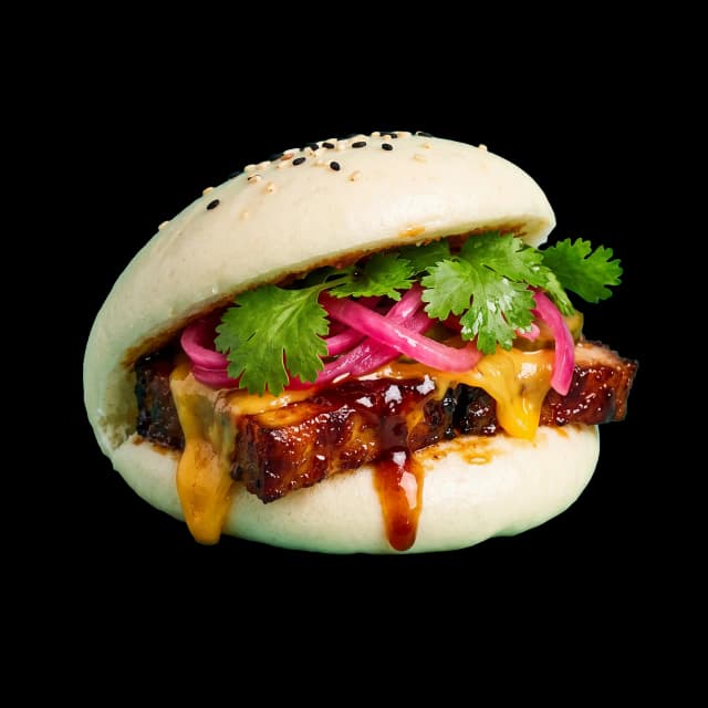Burger bao signature débordant de porc laqué, fromage fondu et coriandre